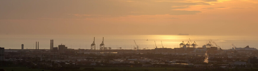 Fototapeta na wymiar Strand von Livorno in Italien mit Industriehafen bei Sonnenuntergang Abendrot