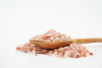 Himalayan pink salt crystals on spoon on white background