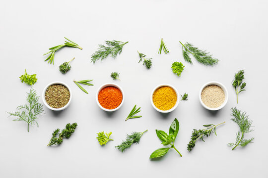 Composition with bowls of spices and fresh herbs on light background