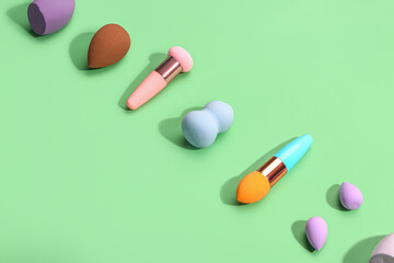 Different makeup sponges on green background