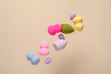 Flying different makeup sponges on beige background