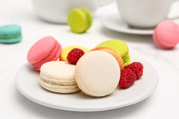 Fototapeta na wymiar Plate with sweet macaroons and raspberries on white background