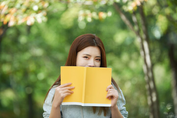 Fototapeta premium A beautiful woman, a college student, reading in a forest park