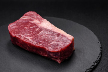 Fresh raw beef striploin steak with salt, spices and herbs