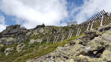 Lawinenschutz Schneerechen aus Holz am Steilhang in den Alpen Berg Schutz vor Lawinen