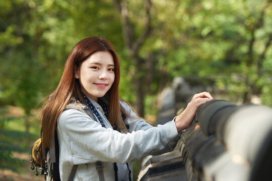 A young woman wearing a camera and backpack traveling to tourist attractions with traditional Korean houses and taking pictures
