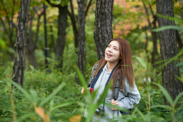 A young woman walking around in the woods taking pictures with a camera and backpack