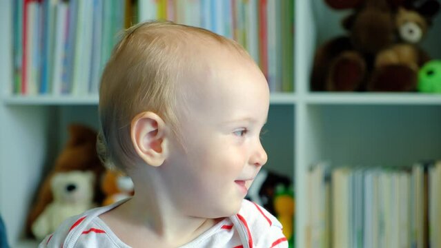 Portrait of a happy one-year-old blonde child with blue eyes at home