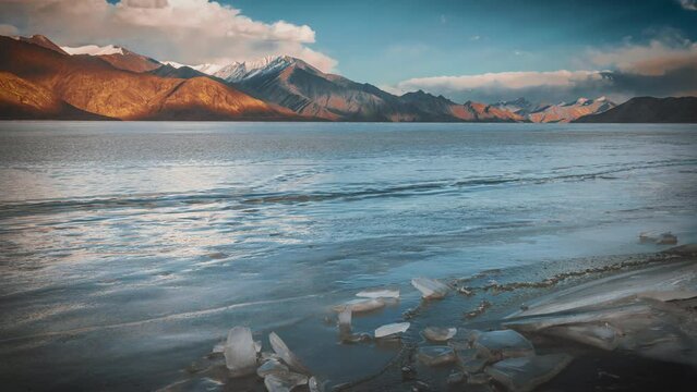 Time-lapse of Clouds Cascading Over the Snow-covered  Pangong Lake in its frozen splendour, with majestic mountains as a backdrop