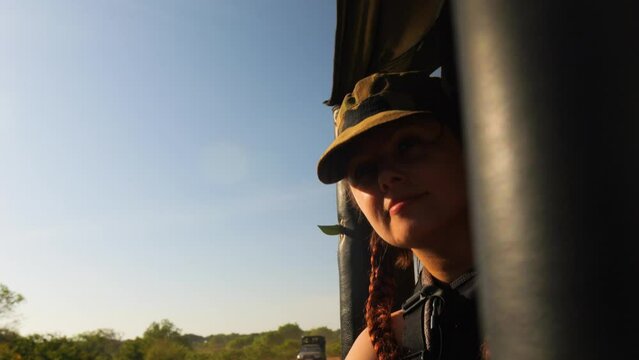 Girl in military cap on jeep safari trip leans out the window. Close up.