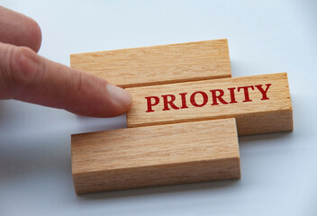 Finger pushing wooden blocks with text - Priority. Priority and business concept