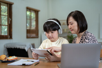 Parents helping children with homework at table at home.