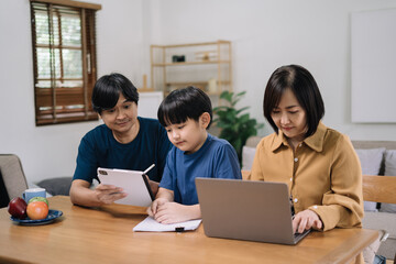 work from home education concept and family at home sitting at desk business woman working on internet in laptop child writing in notebook