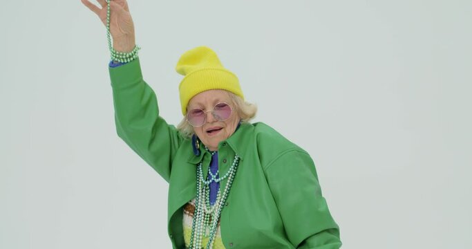 active crazy granny in stylish cool outfit gets pleasure from dancing in studio slow motion Cheerful funky old lady feeling young dancing, listening to music.Happy playful senior woman having fun