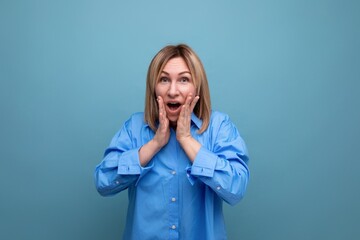 shocked surprised young woman in casual look grabbing her head on blue background