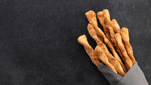 Grissini, bread sticks with parmesan on gray background, top view, place for text