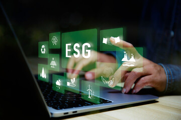 Businessman using laptop analyzing data Net zero in 2050 year for ESG eco concept environmental, social, sustainable, ethical. eco green energy system icon around ESG icon at home office background.