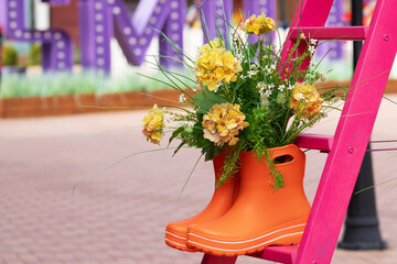 Gardening tools, orange rubber boots on the stairs among the flowers