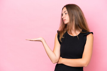 Young caucasian woman isolated on pink background holding copyspace with doubts