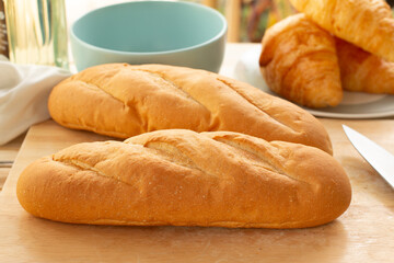 French bread and croissants on a wooden table in the kitchen