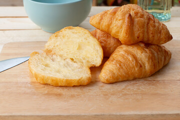 Croissants on a wooden board with a cup of coffee.