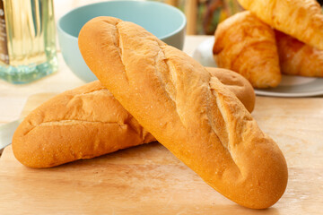 French bread on a cutting board with a cup of tea in the background