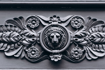 Metal knocker with lion head on the door in vintage style on dark background.