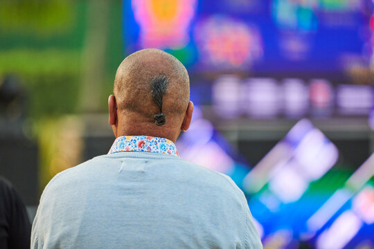 Back view of adult man head with ukrainian chub haircut at outdoor party, rear view of senior man head with oseledets traditional ukrainian haircut, completely shaved man head with long lock of hair