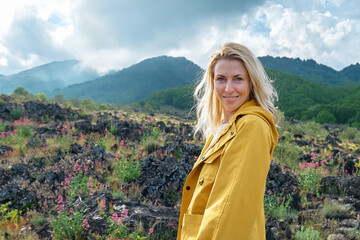 Hiking on tallest volcano in Continental Europe - Etna. Smiling young woman looking at camera near...