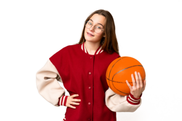 Teenager girl playing basketball over isolated chroma key background posing with arms at hip and smiling