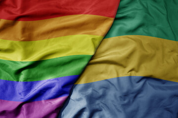 big waving realistic national colorful flag of gabon and rainbow gay pride flag .