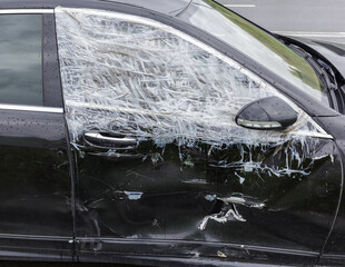Broken window on the passenger side. A broken car window after a burglary from a thief. Vandalism.