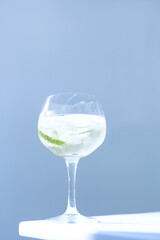 refreshing drink in glass with ice on sunlight and blue background. Ice cubes crystal clear water