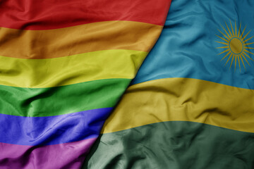 big waving realistic national colorful flag of rwanda and rainbow gay pride flag .