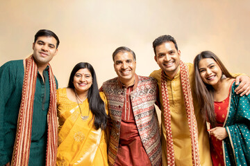 Happy indian family wearing traditional cloths standing isolated on beige background. Celebrating diwali festival, Occasion of wedding, Ethnic wear fashion.