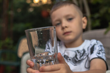 Portrait of a preschool boy drinking water from a glass in the garden