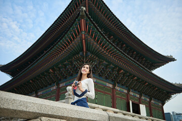 A young foreign woman holding a camera and taking pictures during a trip to Korea