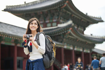 A young foreign woman holding a camera and taking pictures during a trip to Korea	