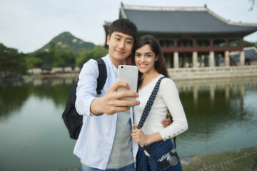 A couple taking pictures of themselves using their smartphones during a trip to Korea