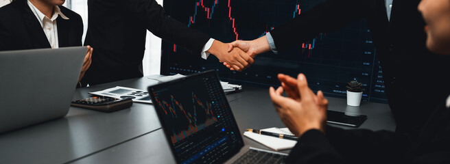 Stock investors celebrate successful profit from selling stock and shaking hand with each other,...