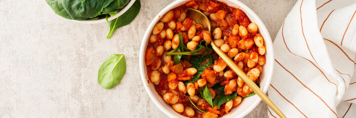 Healthy breakfasts and lunches banner, stewed white beans with carrots, onions and tomatoes with spinach leaves, a bowl of beans and spinach