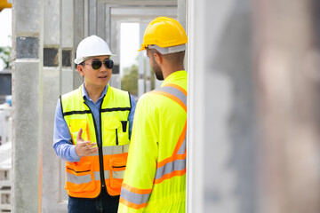 building and construction worker, Hiapanic latin male wearing safety hard hat helmet standing at Prefabricated concrete walls Industry Manufacturing Factory. Unity and teamwork