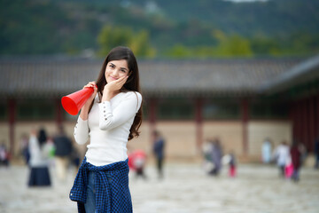 A young woman with a loudspeaker guided by a tour guide at a tourist attraction in Korea