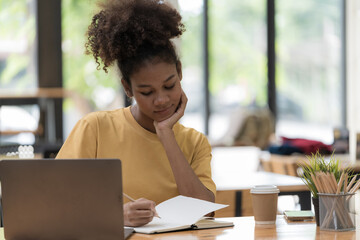 A beautiful African American girl, student or businesswoman sitting at a desk and writing.