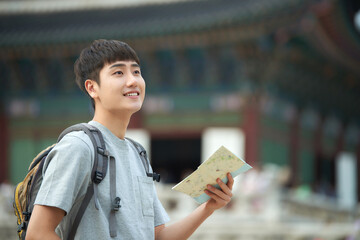 A young man who travels in a traditional Korean village and looks for directions while looking at a map