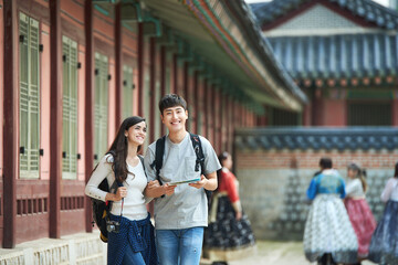 A college student couple looking for their way through a map during a trip to a traditional Korean house