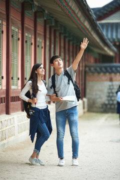 A college student couple looking for their way through a map during a trip to a traditional Korean house