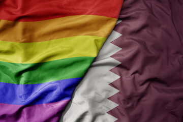 big waving realistic national colorful flag of qatar and rainbow gay pride flag .