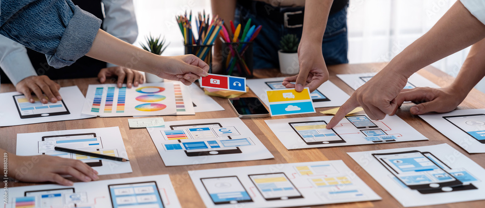 Poster Panorama shot of front-end developer team brainstorming UI and UX designs for mobile app on paper wireframe interface. User interface development team planning for user-friendly UI design. Scrutinize