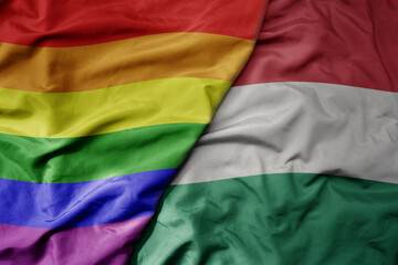 Obraz premium big waving realistic national colorful flag of hungary and rainbow gay pride flag .